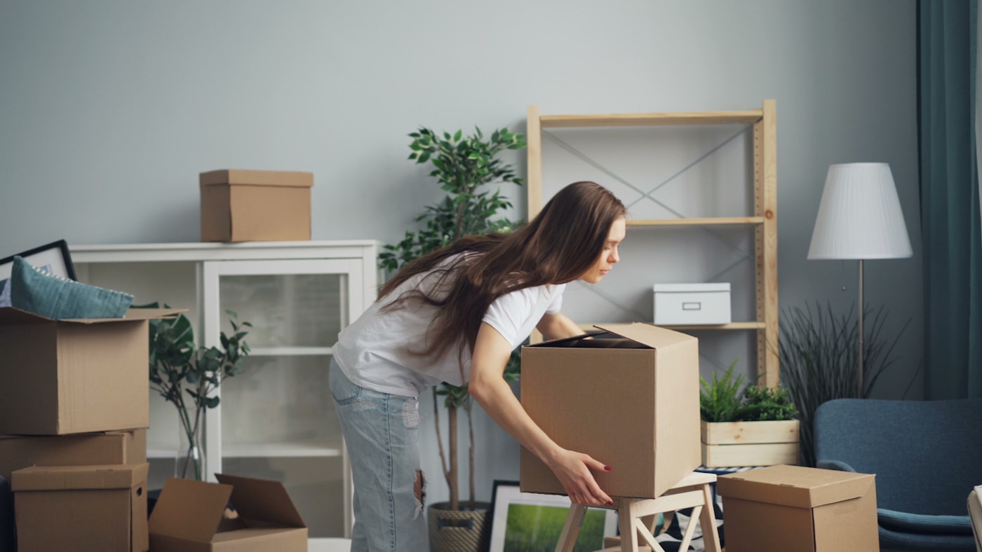 A customer packing boxes in a bright living room on moving day